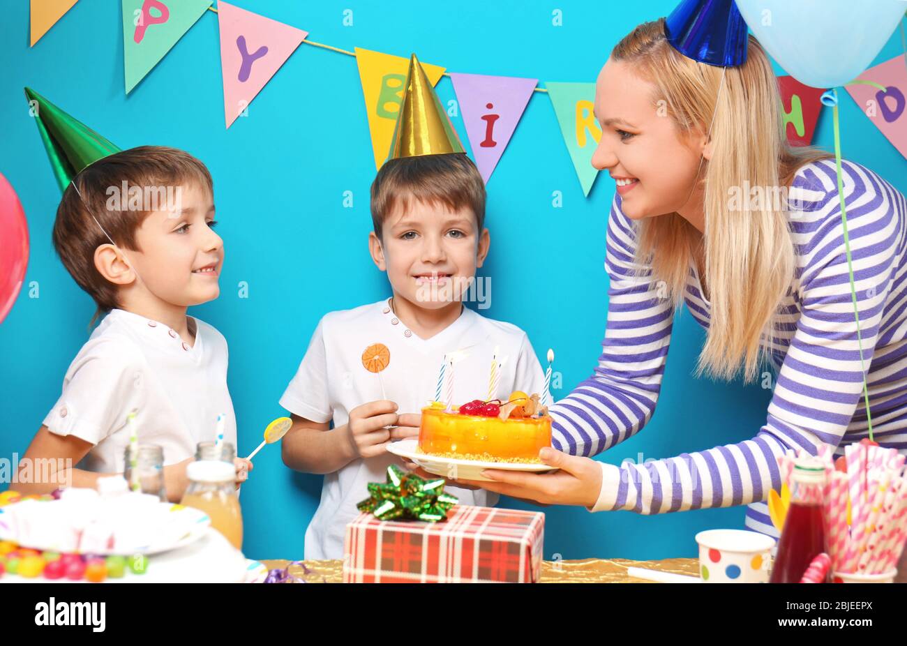 Madre con pastel de cumpleaños para mellizos en la fiesta Fotografía de  stock - Alamy