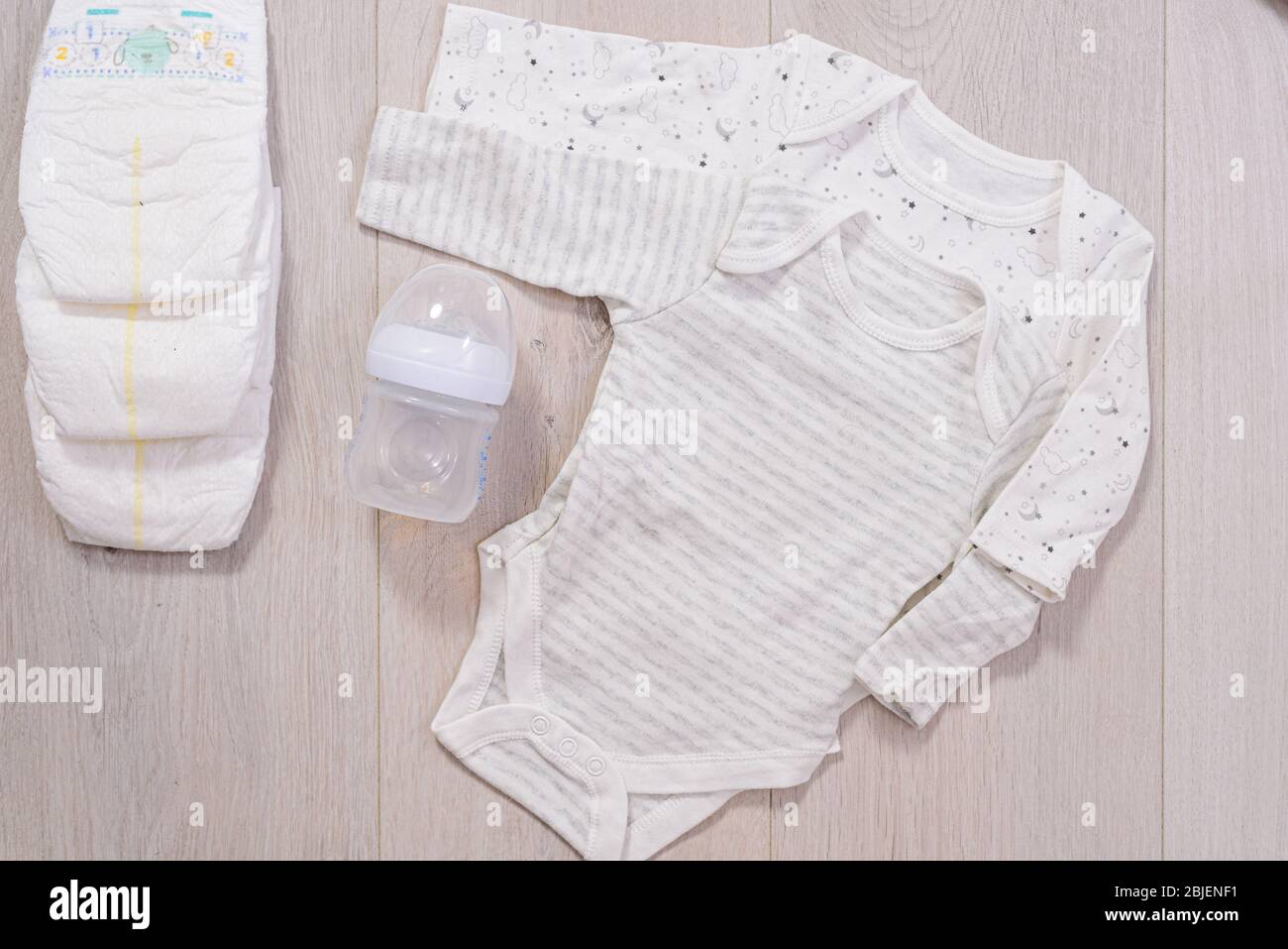 ropa blanca para bebés, pañales y biberón con leche de fondo de madera. recién nacido Fotografía de stock Alamy