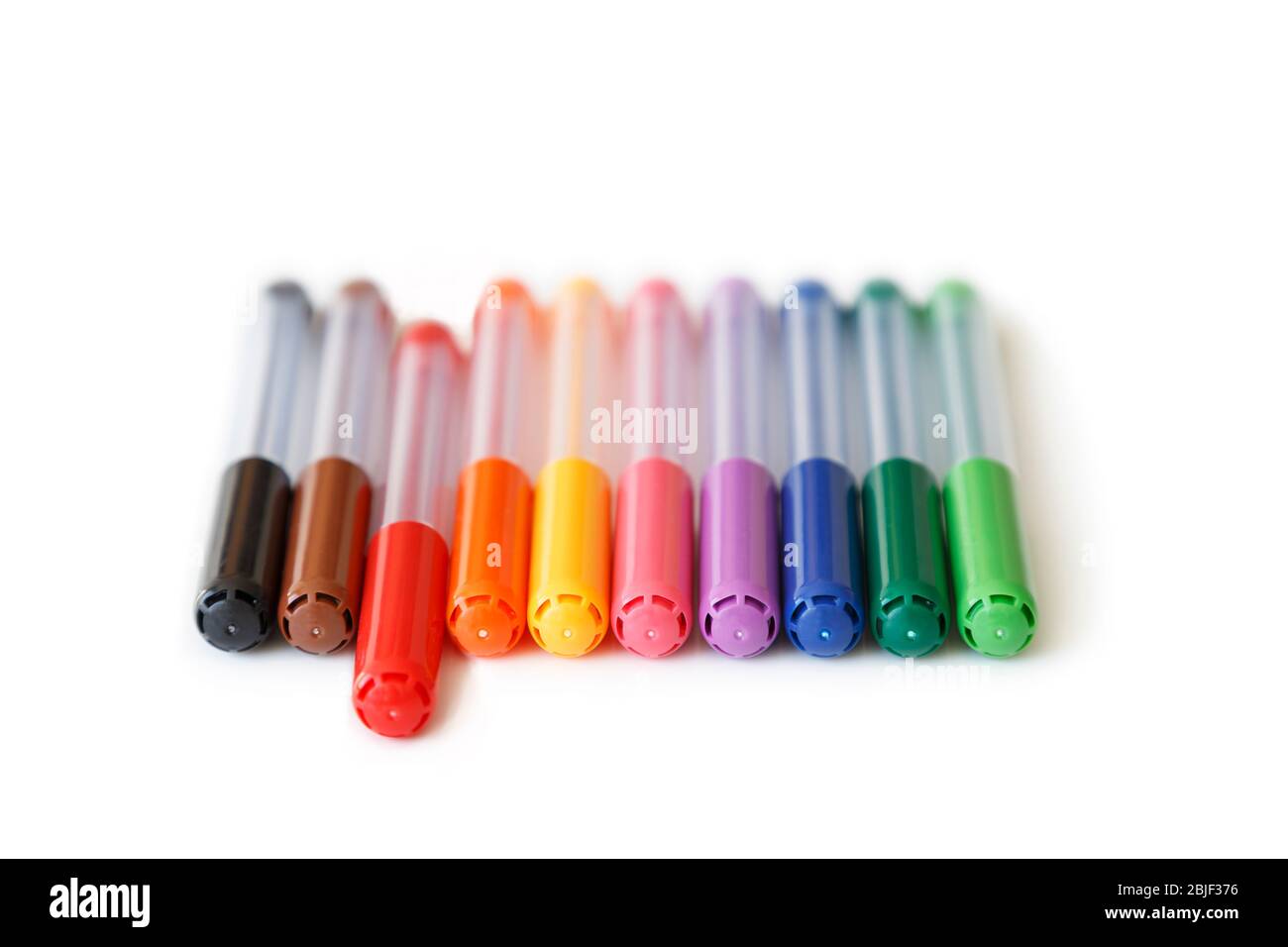 Primer plano de un conjunto de coloridos marcadores de color arco iris en  una vista de fila y ángulo bajo. El marcador rojo es aparte, el concepto de  destacar. Aislado sobre blanco
