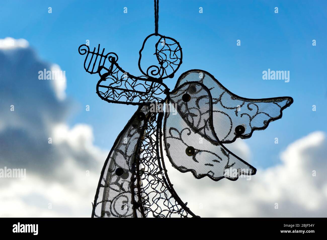 Un ángel de decoración de Navidad con arpa de alambre de acero en frente de  una ventana. Cielo azul con nubes tormentosas Fotografía de stock - Alamy