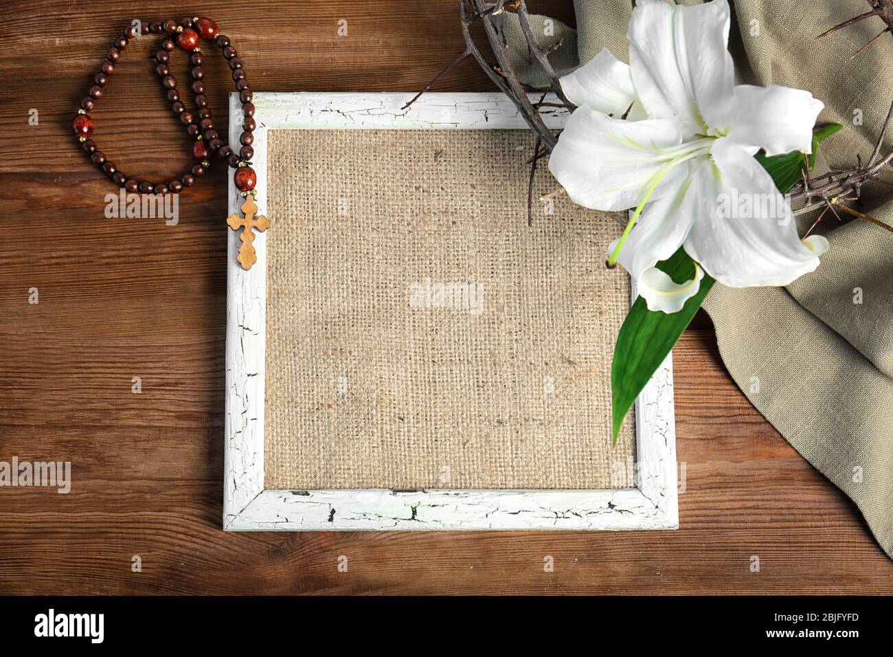 Composición con marco, ensacado, rosario, corona de espinas y lirio sobre  fondo de madera Fotografía de stock - Alamy