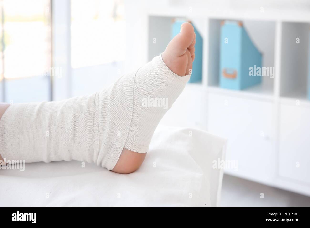 Mujer joven con pierna vendada en clínica, closeup Foto de stock