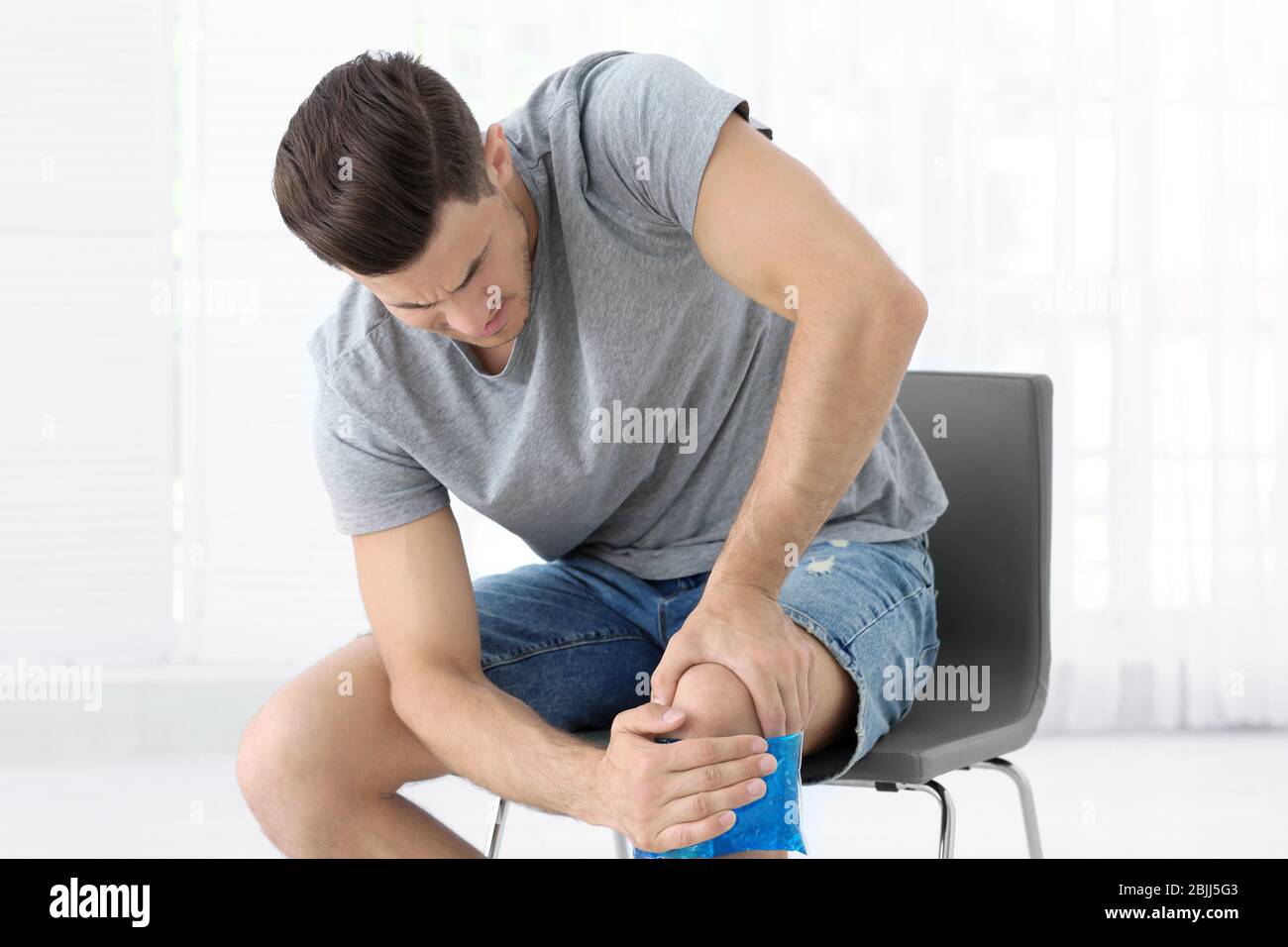 Hombre joven aplicando compresas frías en la pierna en casa Fotografía de  stock - Alamy