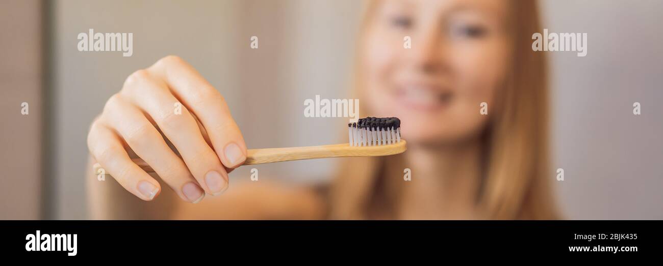 Mujer joven cepillando sus dientes con una pasta negra con carbón activo, y  cepillo negro en SU BANNER del baño, FORMATO LARGO Fotografía de stock -  Alamy
