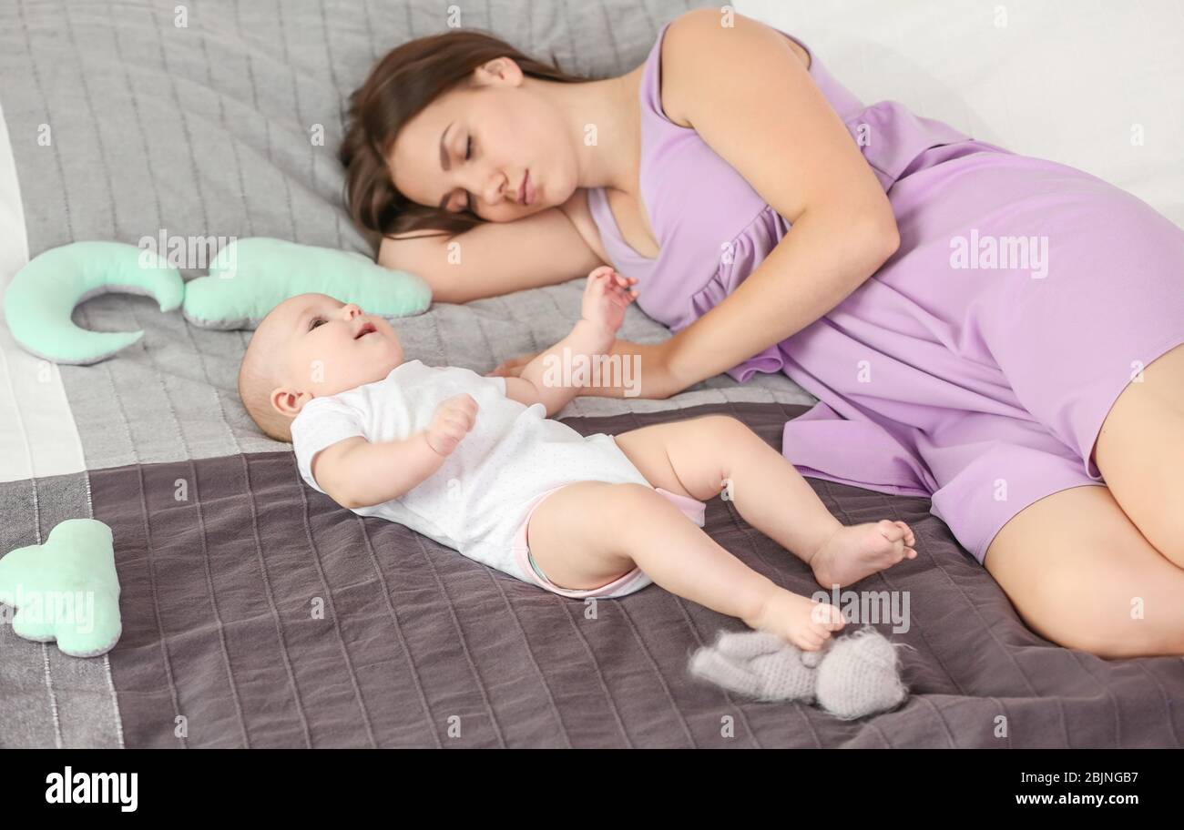 Lindo despertar bebé cerca de la madre dormida en casa Foto de stock