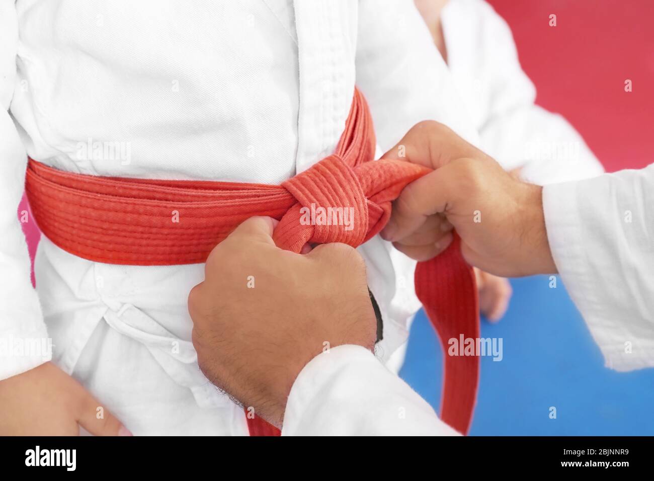 Instructor de Karate que ata el cinturón en la cintura del niño, primer  plano Fotografía de stock - Alamy