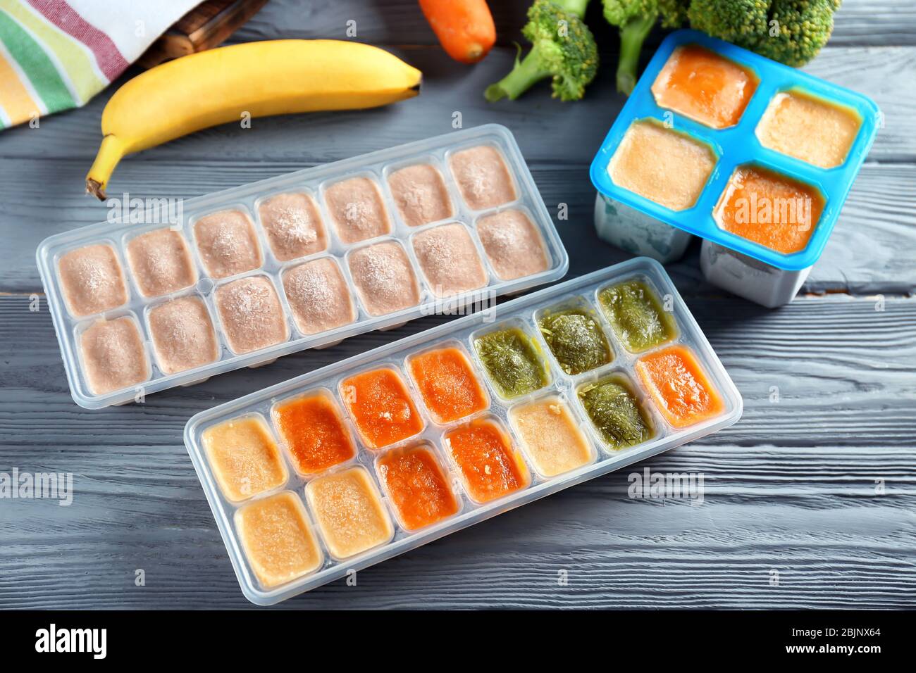 Bandejas de hielo con verduras congeladas y puré de frutas sobre mesa de  madera Fotografía de stock - Alamy