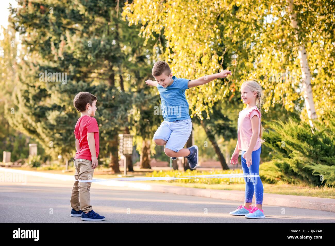 Adorables niños jugando al juego elástico al aire libre Fotografía de stock  - Alamy