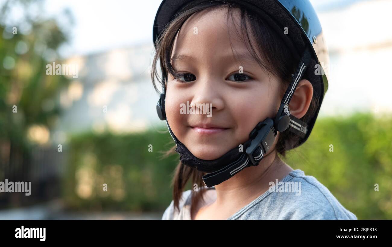 Sonriente lindo niño asiático con casco de seguridad en el parque. Actividad deportiva al aire libre para niños. Foto de stock