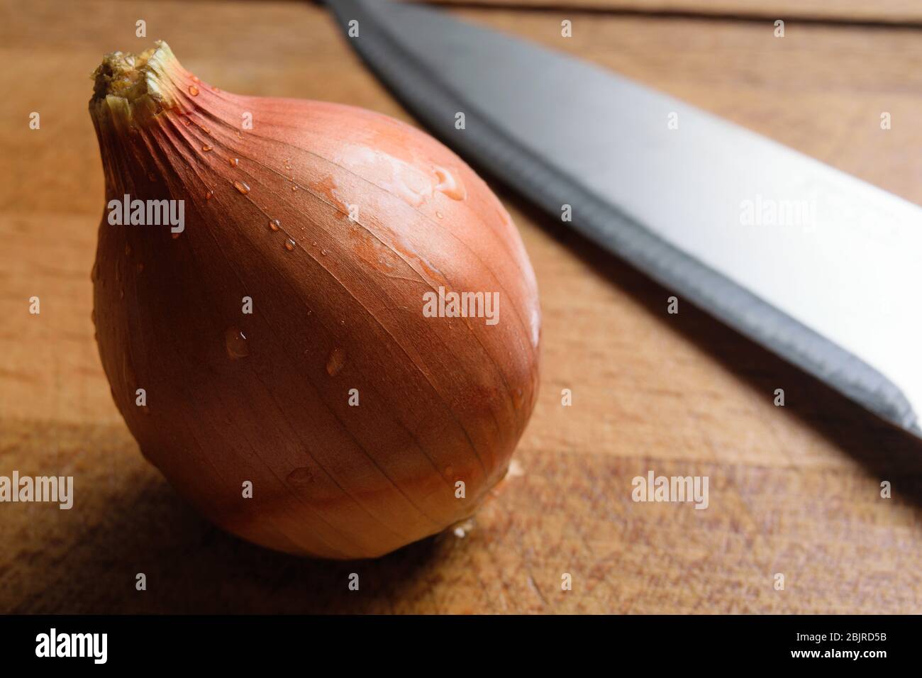 cebolla acostada en una tabla de cortar con un cuchillo de cerca Foto de stock