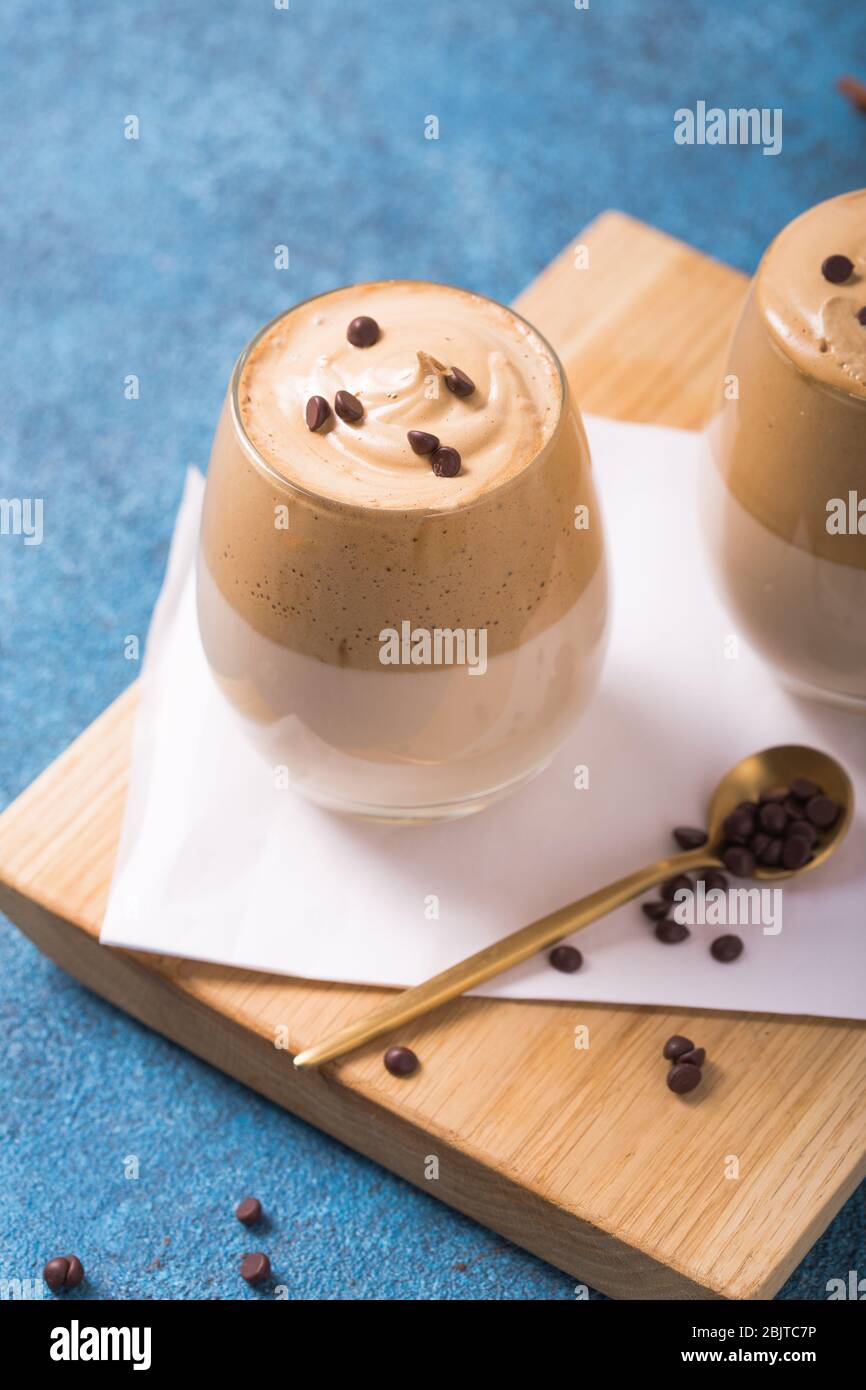 El café espumoso Dalgona es una bebida surcoreana con café instantáneo,  azúcar y leche batidos, sobre una mesa de concreto azul Fotografía de stock  - Alamy