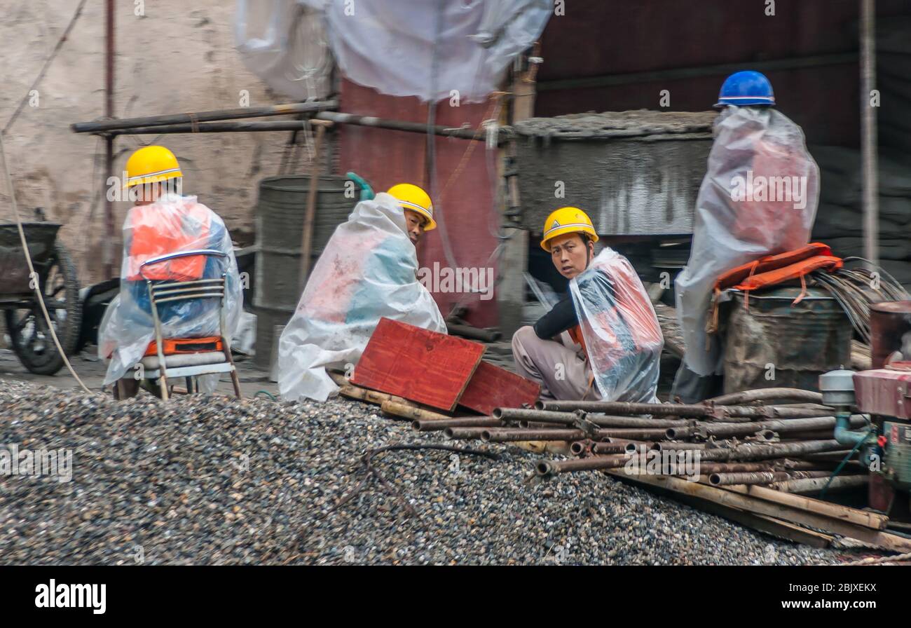 Wuchan, China - 7 de mayo de 2010: Dicui o Emerald Gorge en el río Daning. Cierre de trabajadores de construcción sorprendidos con cascos amarillos, cubiertas de plástico para la lluvia Foto de stock