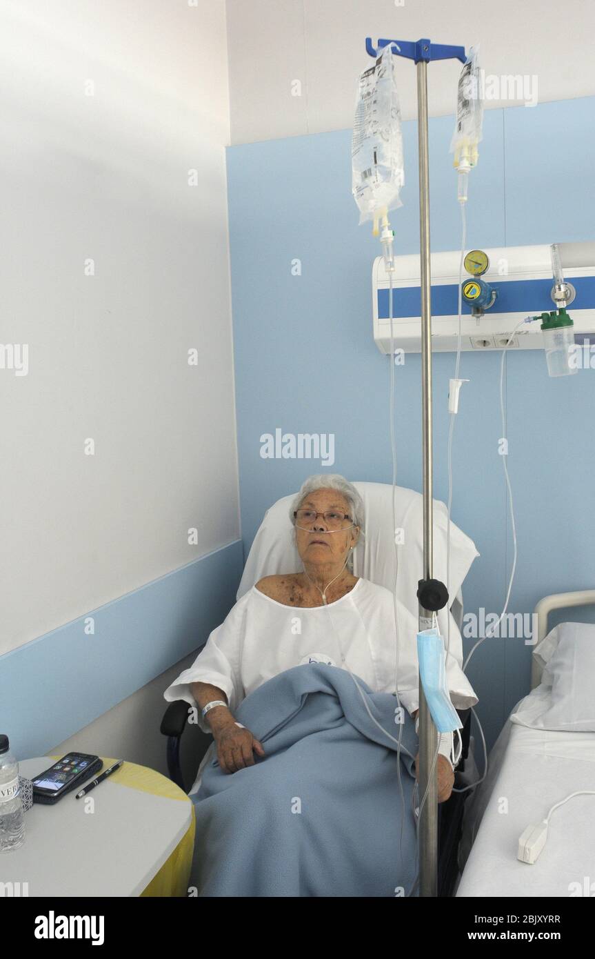 Mujer sentada junto a la cama, conectada con diferentes vías a medicamentos  intravenosos en el hospital Plató de Barcelona Fotografía de stock - Alamy