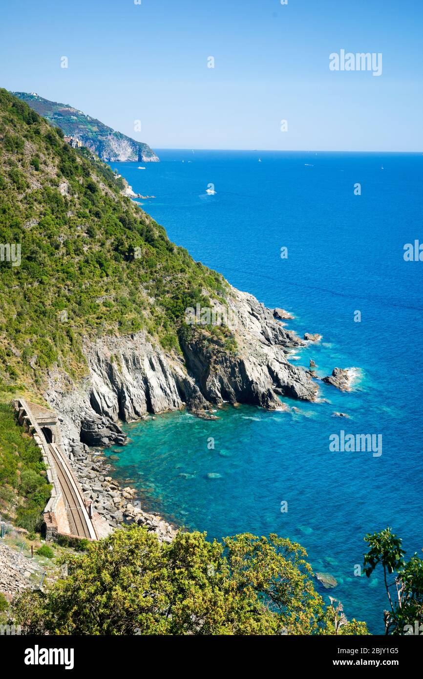Pistas de tren a lo largo de la costa visible en la famosa ruta de senderismo entre Corneglia y los pueblos de Vernazza, Cinque Terre, Italia, Europa Foto de stock