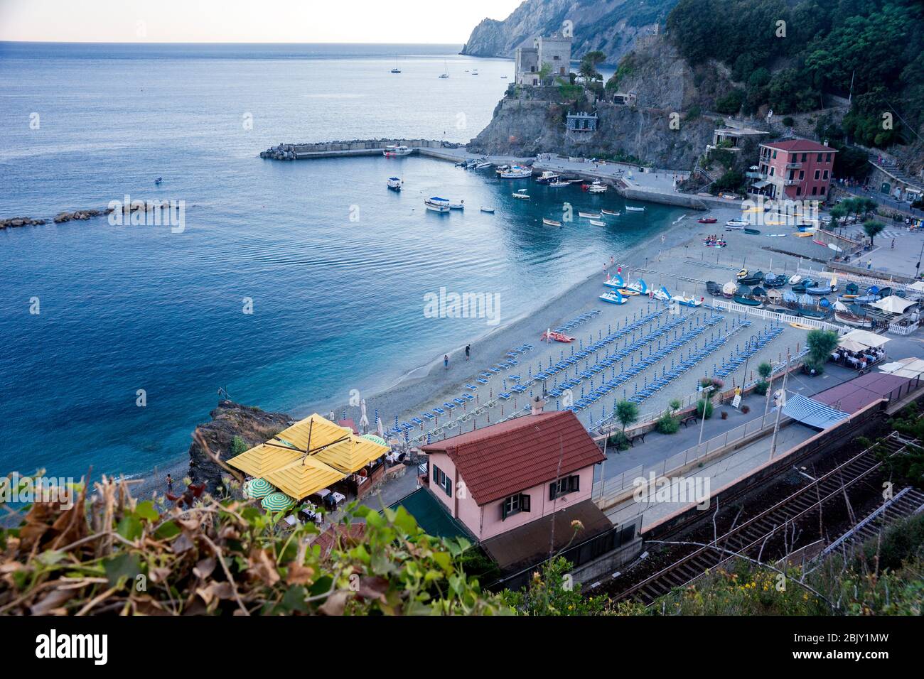 Vista general de la bahía de Monterosso con sillas de playa, barcos y vías de tren, Cinque Terre; Italia; Europa Foto de stock