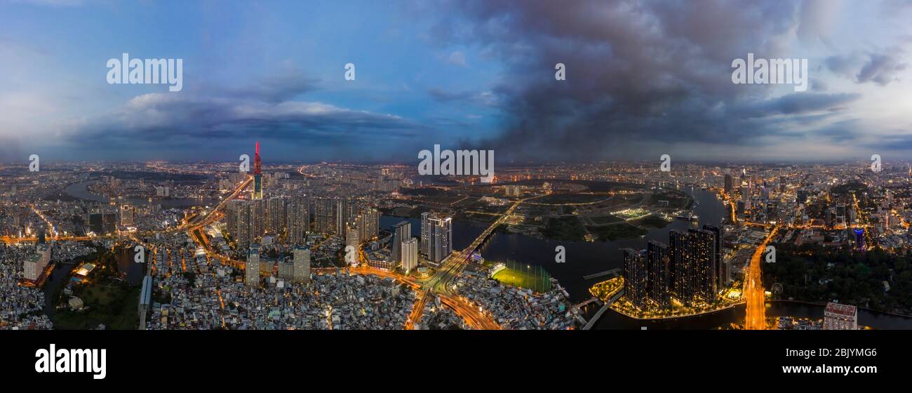 Panorama aéreo nocturno de Saigón, Vietnam con nuevos desarrollos de altura en el frente del río, el centro de la ciudad y la infraestructura con las luces de la ciudad encendidas Foto de stock
