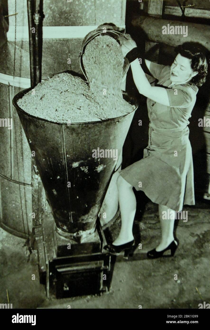 La esposa de la casa está llenando la tolva del quemador de aserrín de la  casa, 1942 (23681690775 Fotografía de stock - Alamy