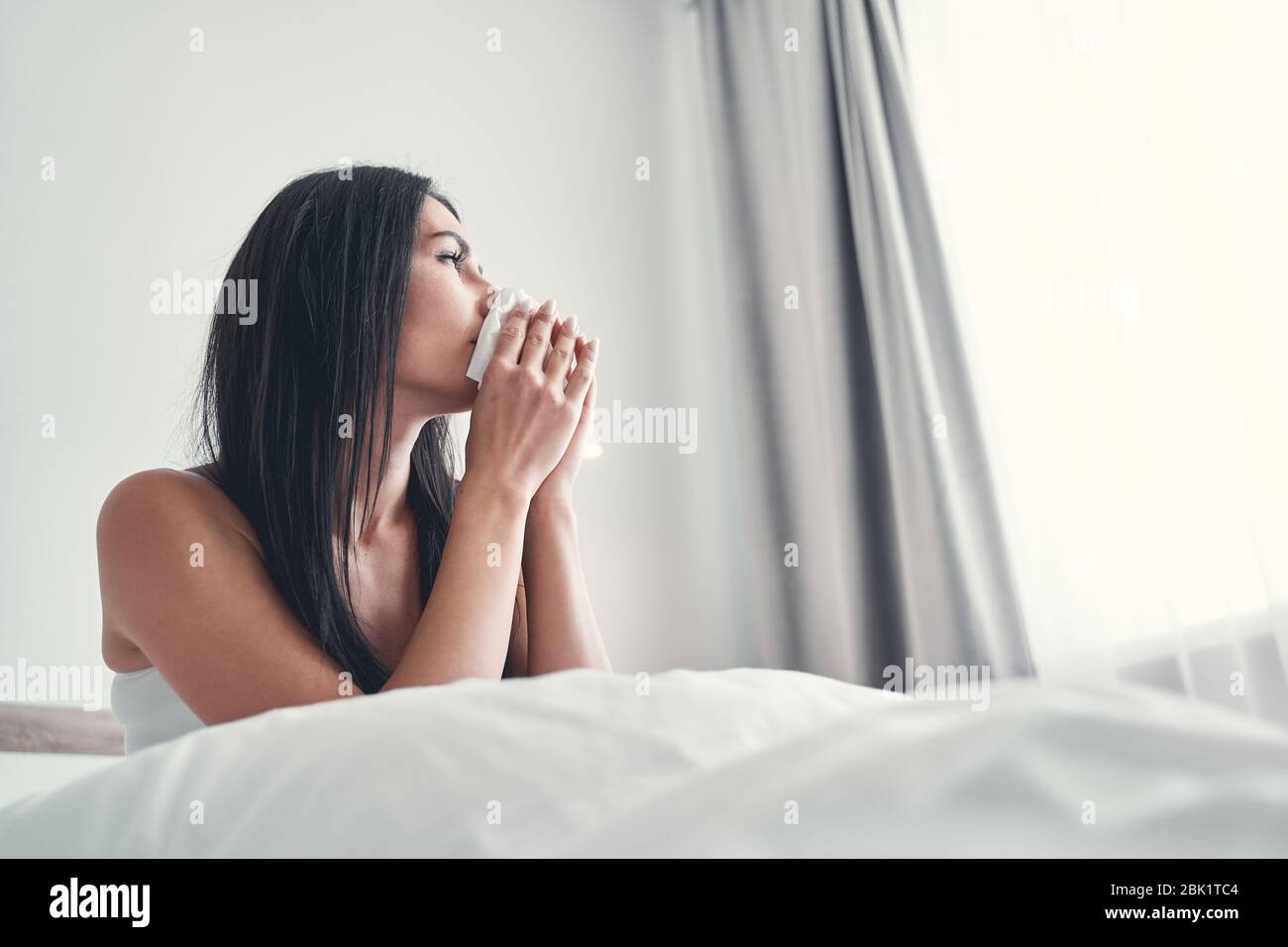 Tierna niña de pelo largo mirando a un lado en la ventana Foto de stock