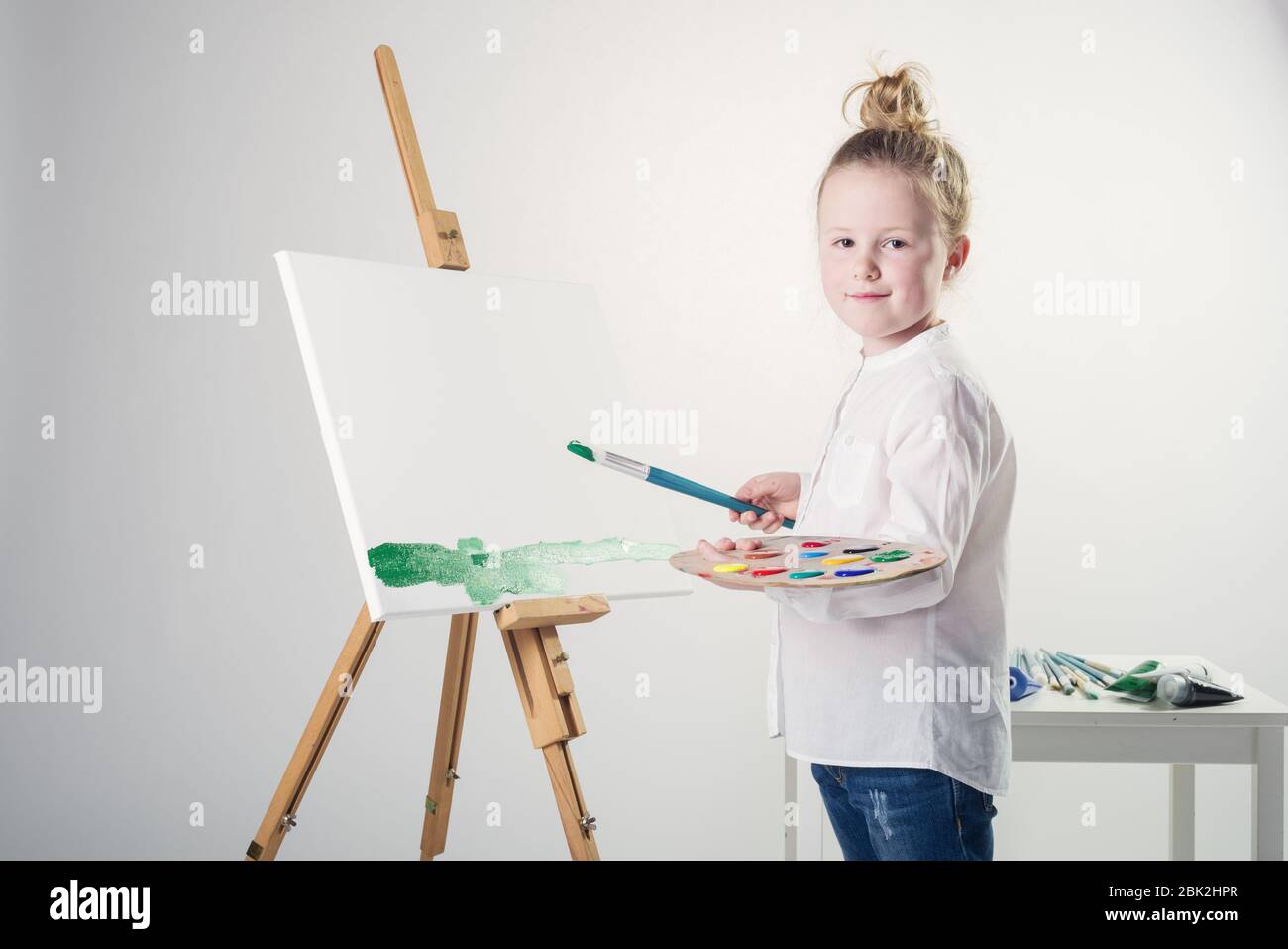 Imágenes en color pintadas por una hermosa chica rubia sobre un fondo blanco. Foto de stock