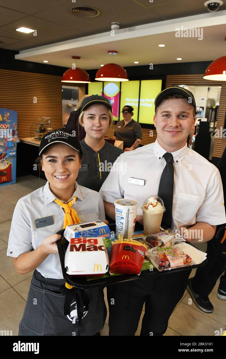 Retrato de tres miembros del personal del restaurante McDonalds en uniforme  en el Reino Unido, mirando la cámara y sosteniendo bandejas de comida  Fotografía de stock - Alamy