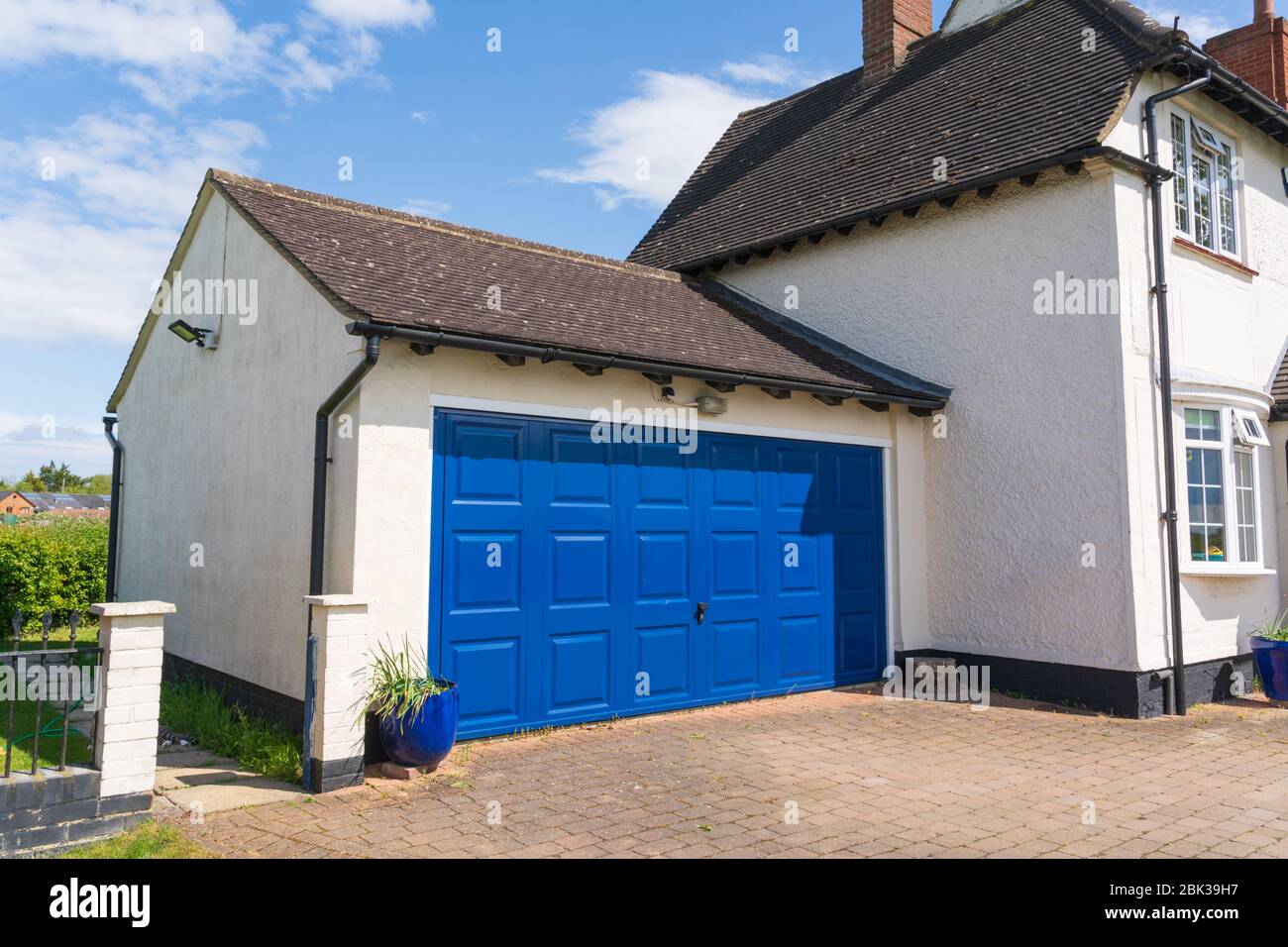 Exterior de un garaje doble con un metal azul y puerta de arriba y de encima adjunta a una casa. Hertfordshire. REINO UNIDO Foto de stock
