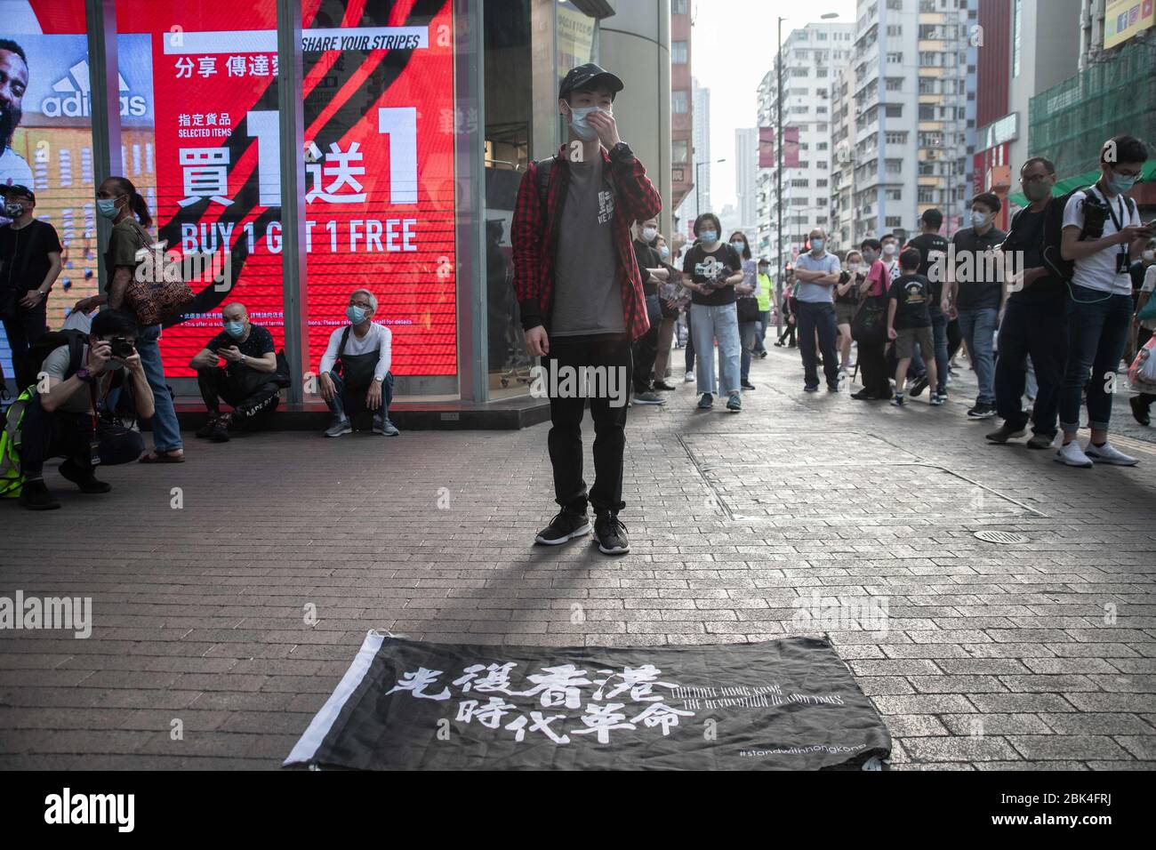 Un manifestante se encuentra frente a una bandera con un mensaje a favor de la independencia mientras llevaba una máscara facial como precaución contra el virus de la corona, durante la manifestación.defendiendo la prohibición de reunión que siguió a la covid pandemia de 19, los manifestantes se manifiestan contra el gobierno de Hong Kong y la jefa ejecutiva Carrie Lam el día del Trabajo, 1 de mayo. Foto de stock