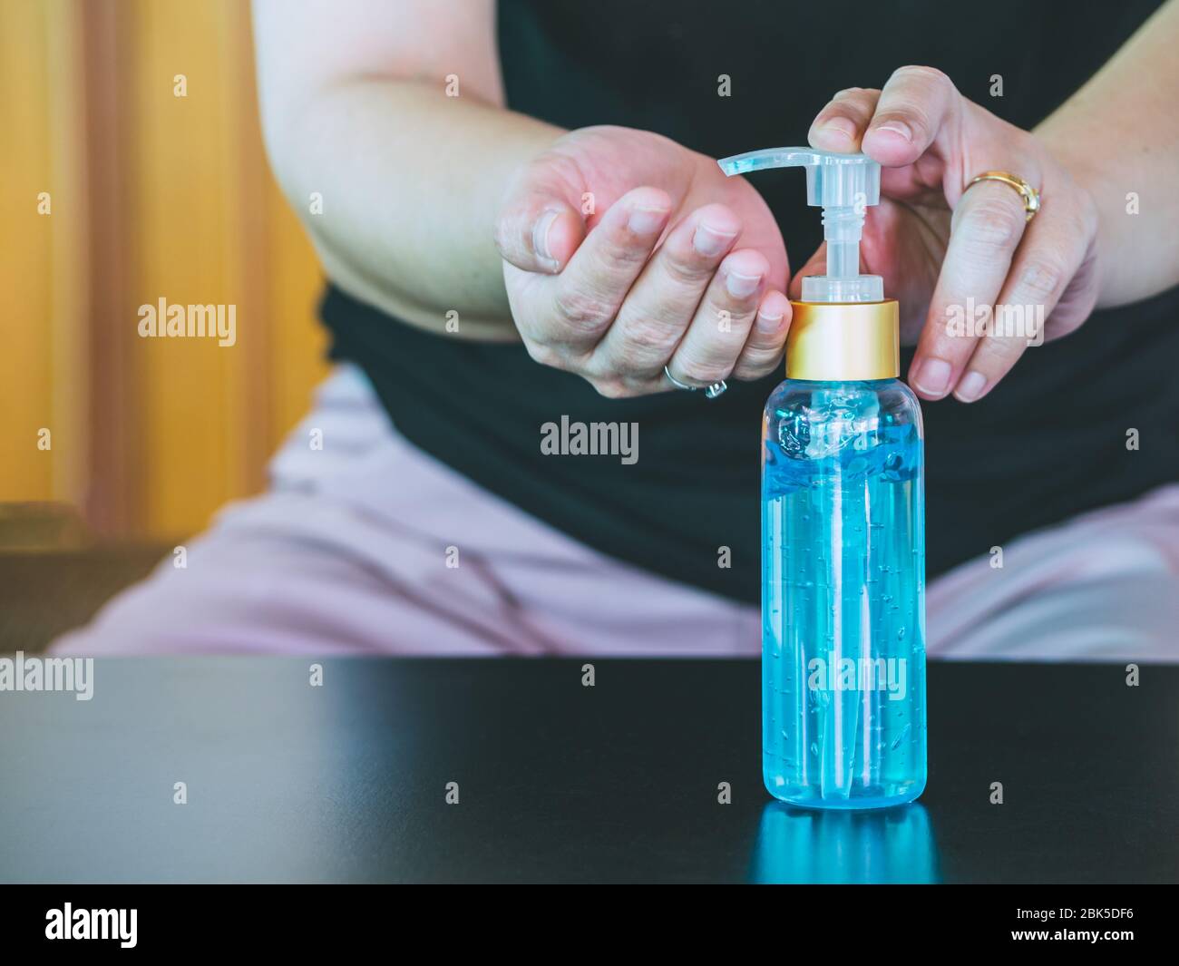 Mujer de Asia presionando gel de alcohol de la botella y gel desinfectante de lavado para lavar a mano para limpiar y eliminar bacterias, contaminación del aire sucio y virus para p Foto de stock