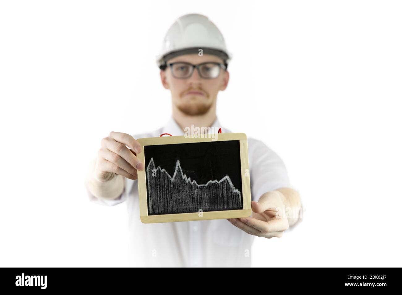 El ingeniero de minería que sostiene la tableta con el gráfico que cae mira tristemente a la cámara Foto de stock
