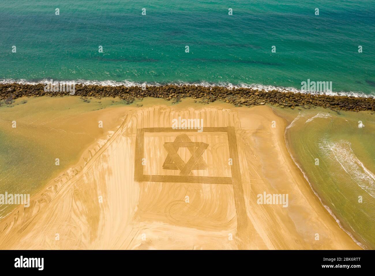Bandera de Israel diseñado en arena de playa para el día de independencia durante el bloqueo del virus de la corona, vista aérea. Foto de stock