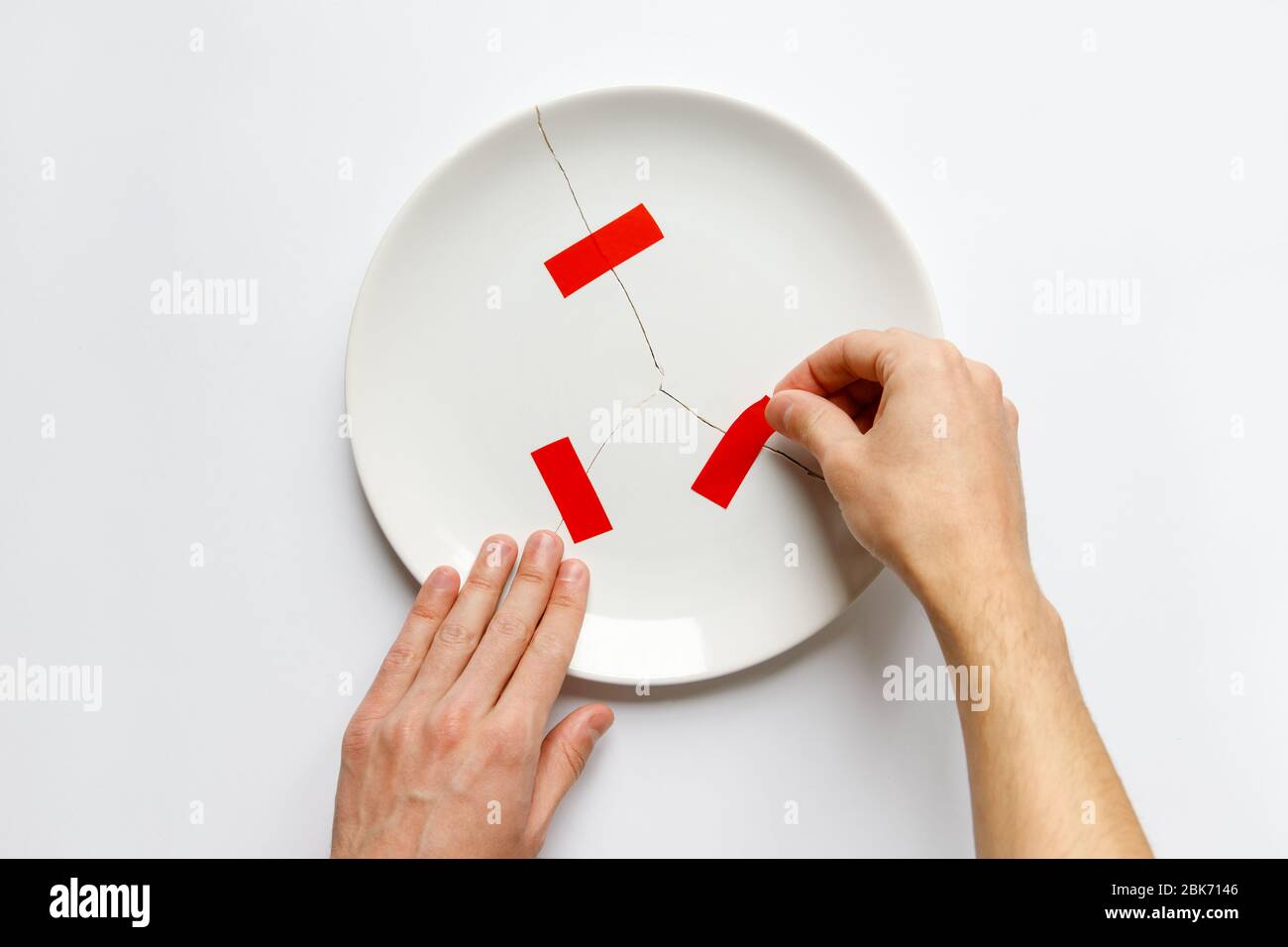 Vista superior de manos de hombre sosteniendo un plato blanco roto