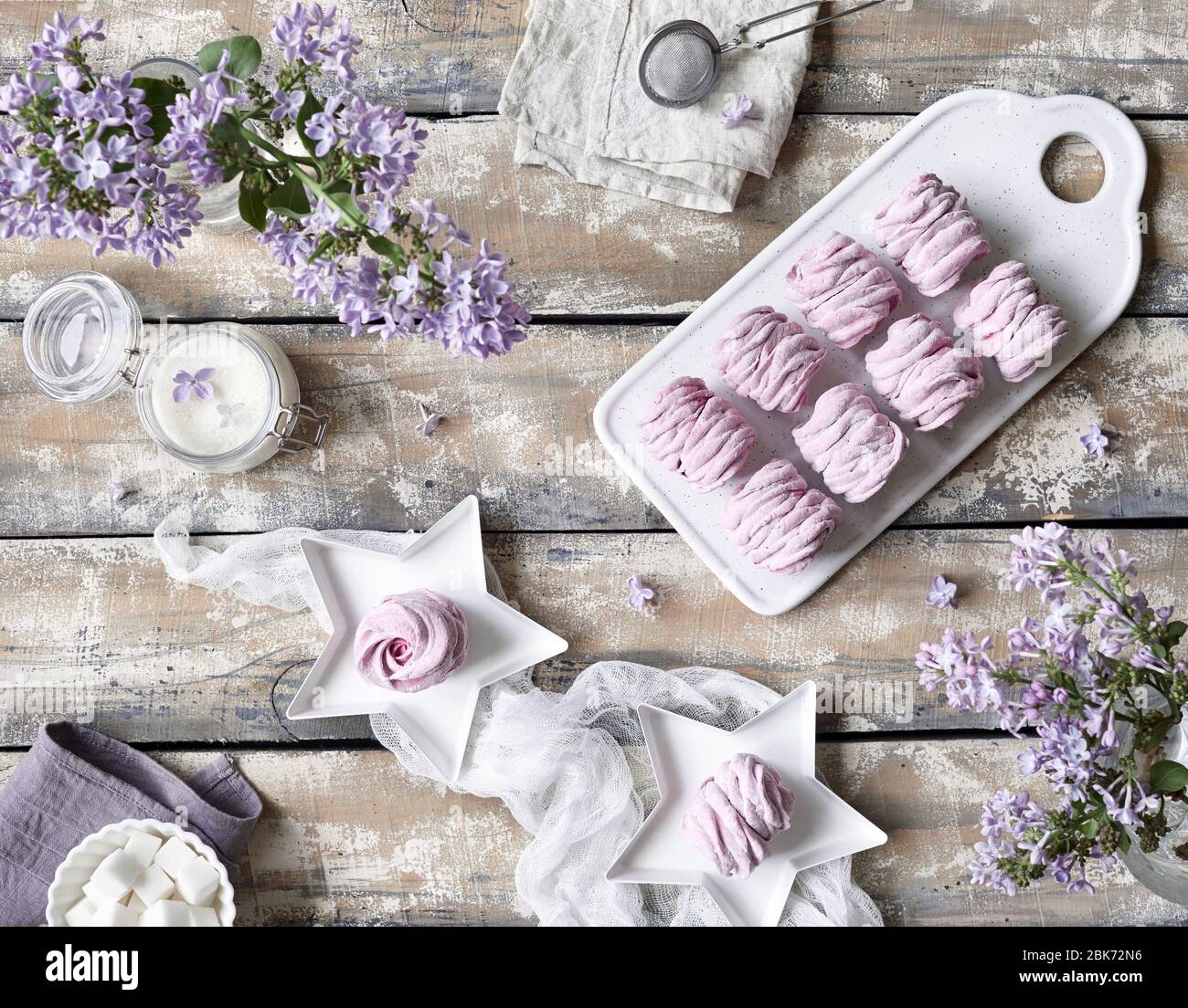 Violeta dulce casero Zephyr o Marshmallow de grosella negra cerca de las flores lilas en la mesa de madera vista en colores pastel violeta Foto de stock