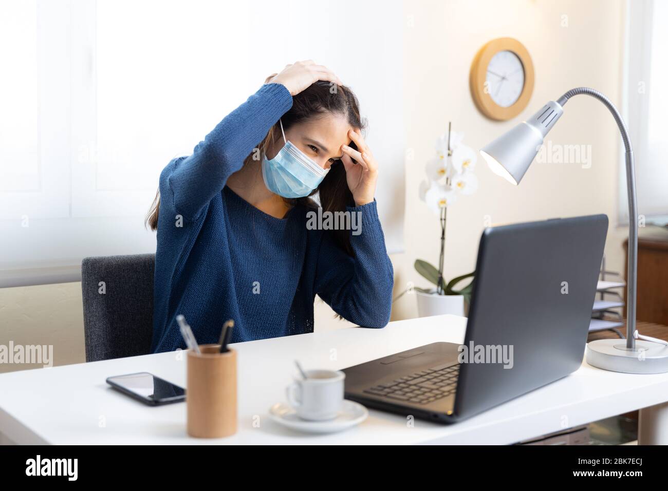 Un estudiante adolescente con máscara facial se queja de dolor de cabeza con la computadora en casa Foto de stock