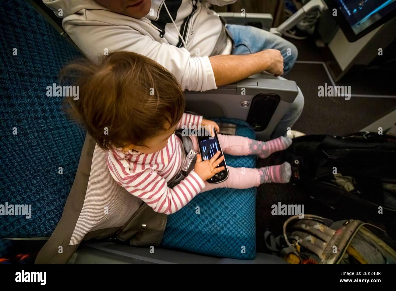 entretenimiento a bordo del avión en vuelo. bebé sentado en el avión en el asiento y jugar divertido en el sistema multimedia remoto. Foto de stock