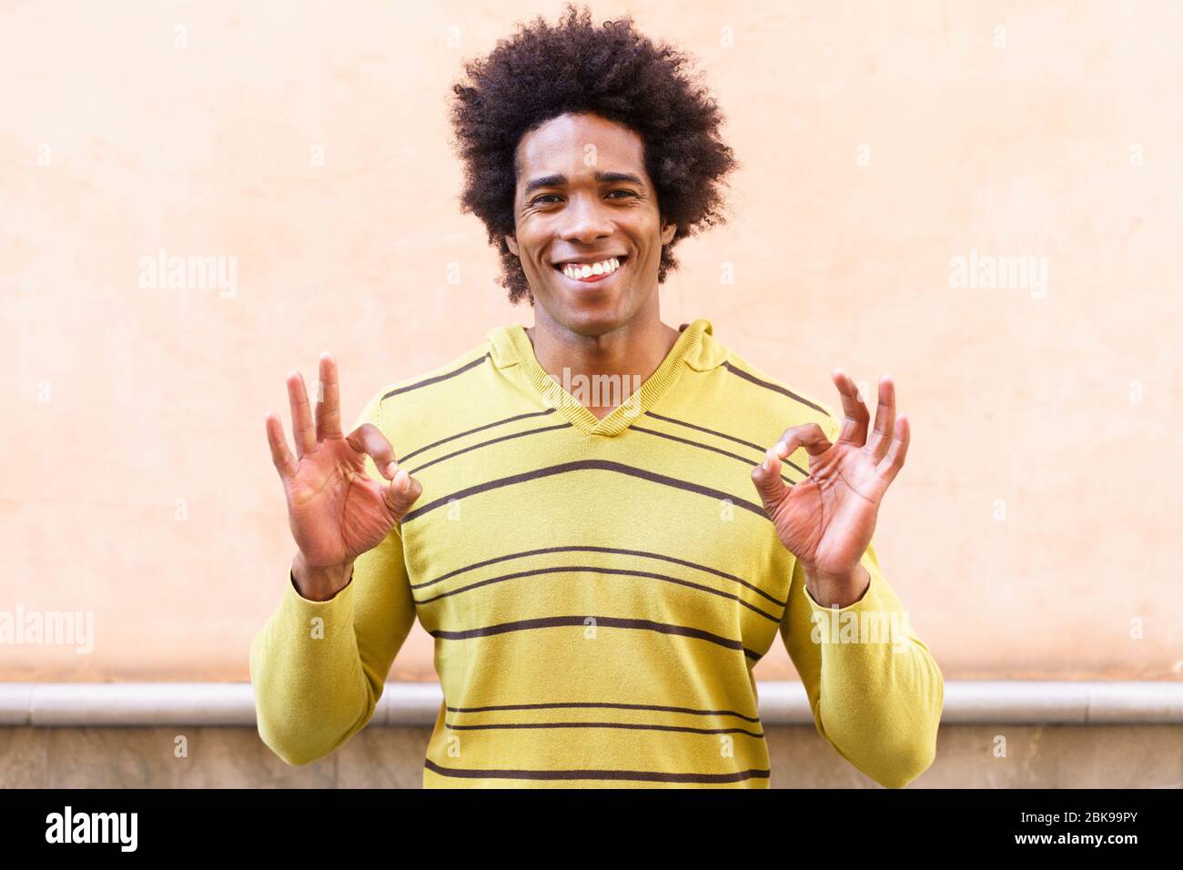 Hombre negro con pelo afro poniendo una expresión divertida Foto de stock