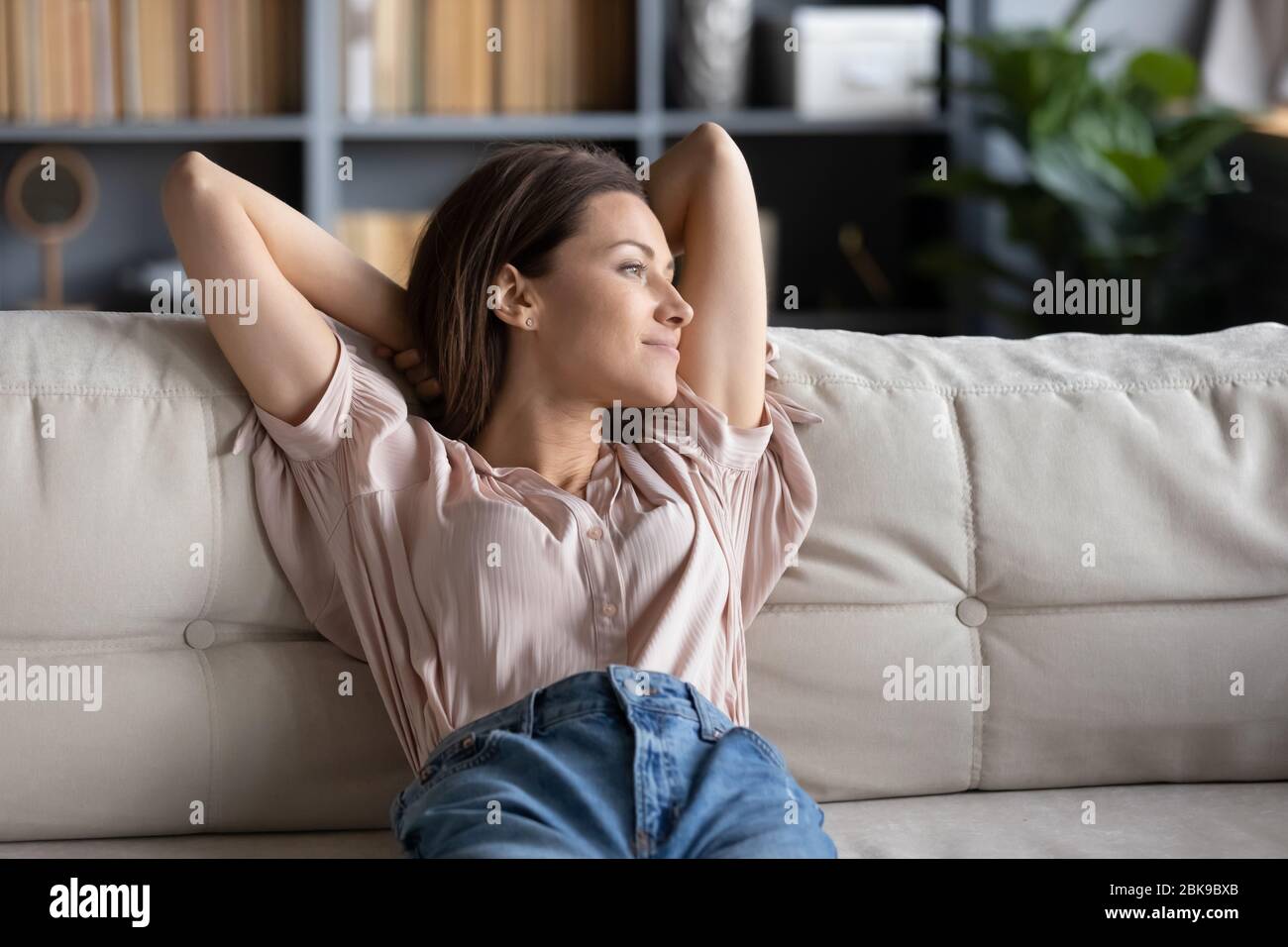 Mujer joven tranquila relajándose en el sofá en casa Foto de stock
