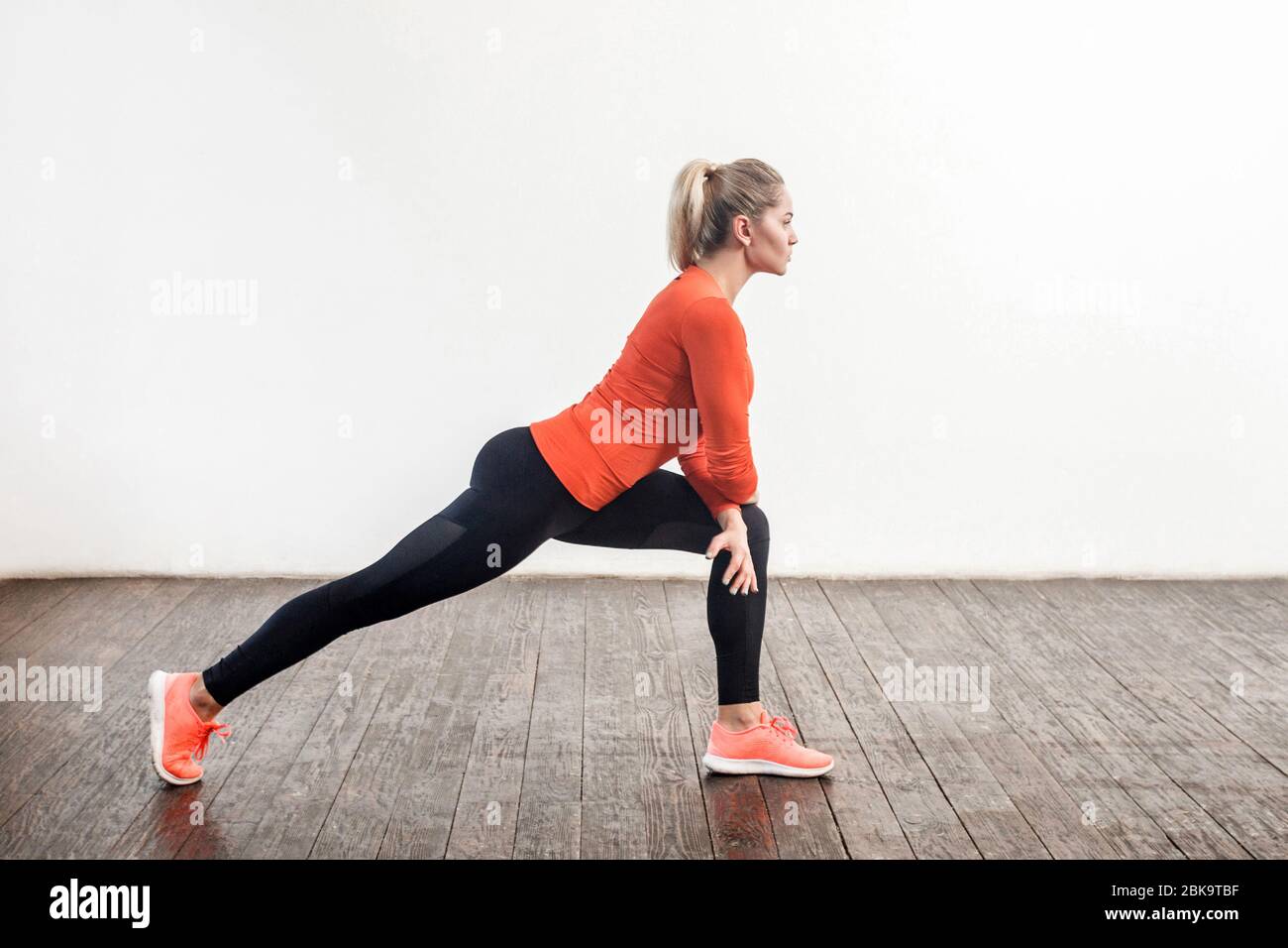 Mujer atractiva atlética delgada con ropa deportiva ajustada haciendo ejercicios de estiramiento de para una mayor flexibilidad, ejercicio en la parte inferior del cuerpo. Atención de salud, deportivo Fotografía de