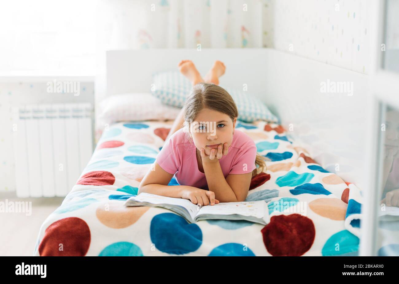 Bonita niña de 8-9 años se encuentra en la cama, leyendo el libro.  Comodidad, concepto de hogar acogedor. Estilo de vida Fotografía de stock -  Alamy