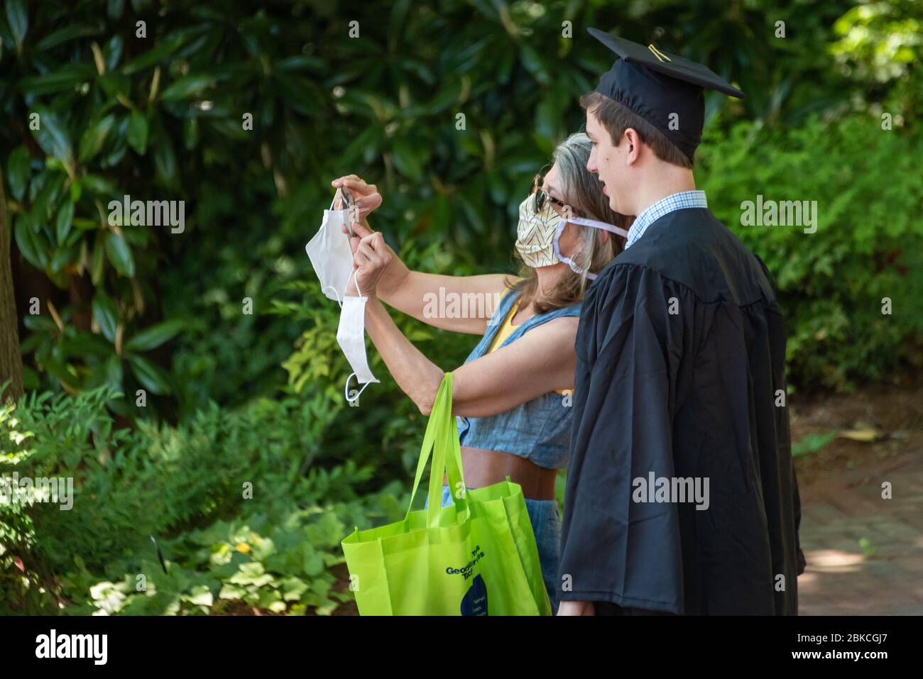 Madre con máscara facial e hijo graduado de la universidad se hacen selfie juntos en Georgia Tech en Atlanta, Georgia durante la pandemia del coronavirus. (EE. UU.) Foto de stock