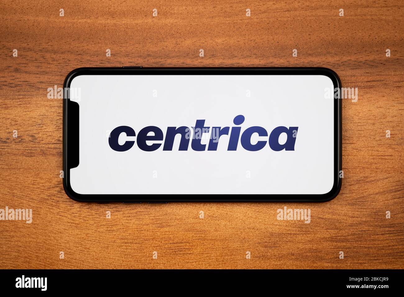 Un smartphone que muestra el logotipo de Centrica descansa sobre una mesa de madera plana (sólo para uso editorial). Foto de stock