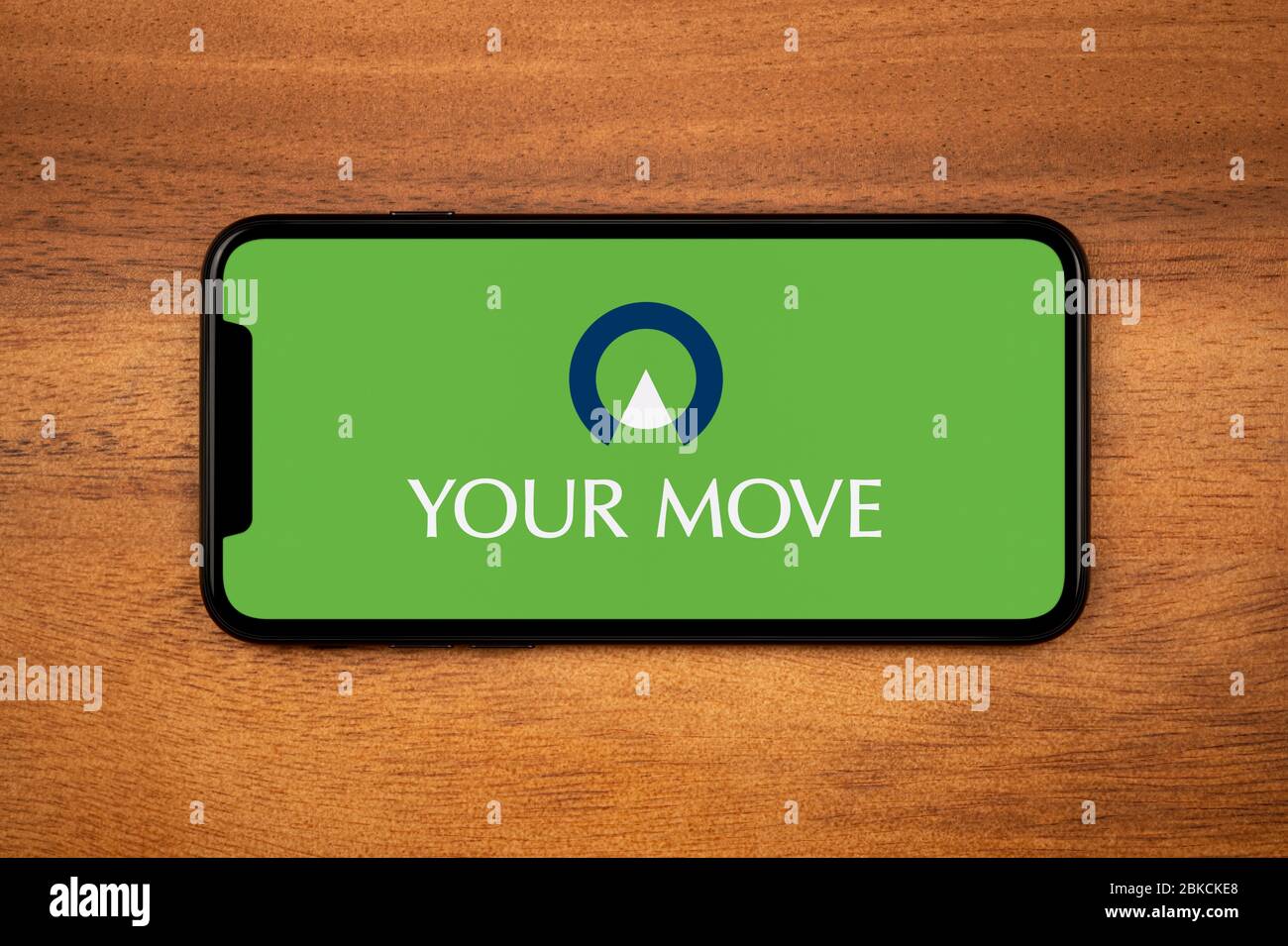 Un smartphone que muestra el logotipo de su movimiento descansa sobre una mesa de madera plana (sólo para uso editorial). Foto de stock
