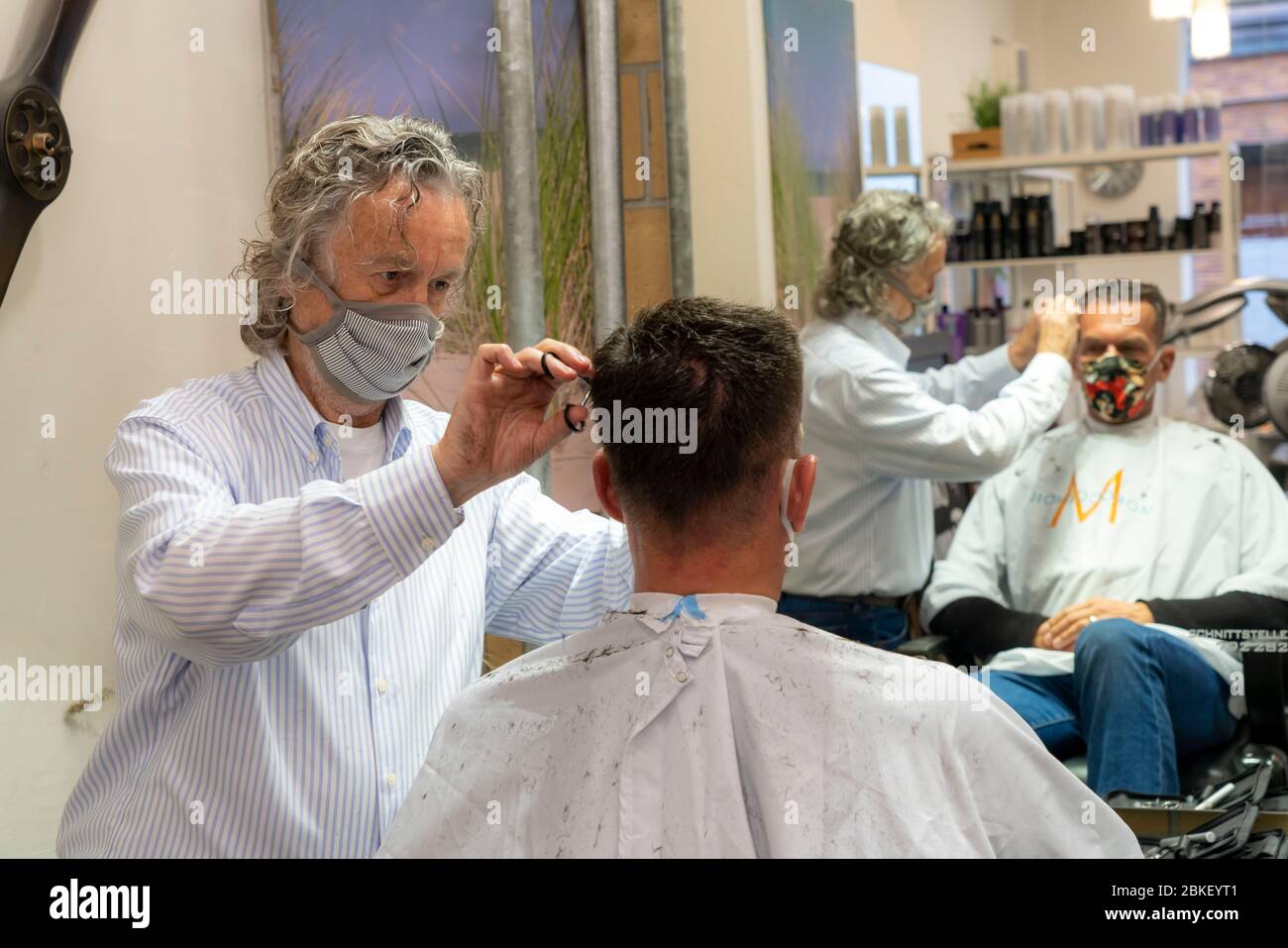 Peluquería en Essen-Rüttenscheid, primer cliente después de 6 semanas, tienda cerrada por crisis corona, maestro peluquería y cliente con boca n Foto de stock