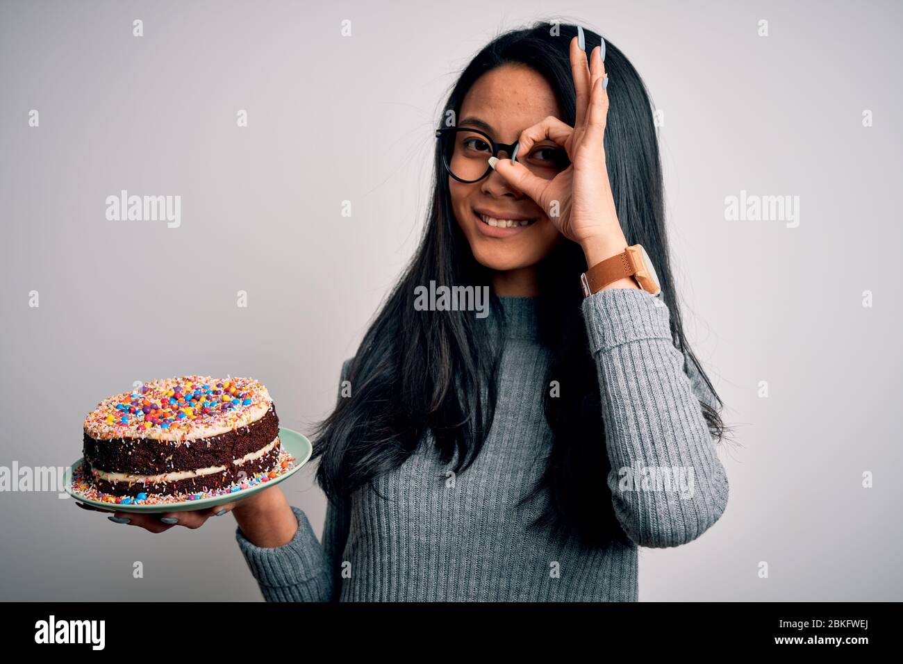 Joven hermosa China celebración de pastel de cumpleaños de pie sobre fondo  blanco aislado con cara feliz sonriendo haciendo ok signo con la mano en el  ojo Fotografía de stock - Alamy