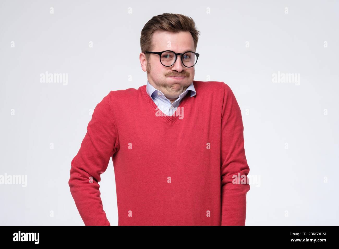 Hombre joven guapo en gafas y suéter rojo aislado sobre respiración de blanca. Disparo de Fotografía stock - Alamy