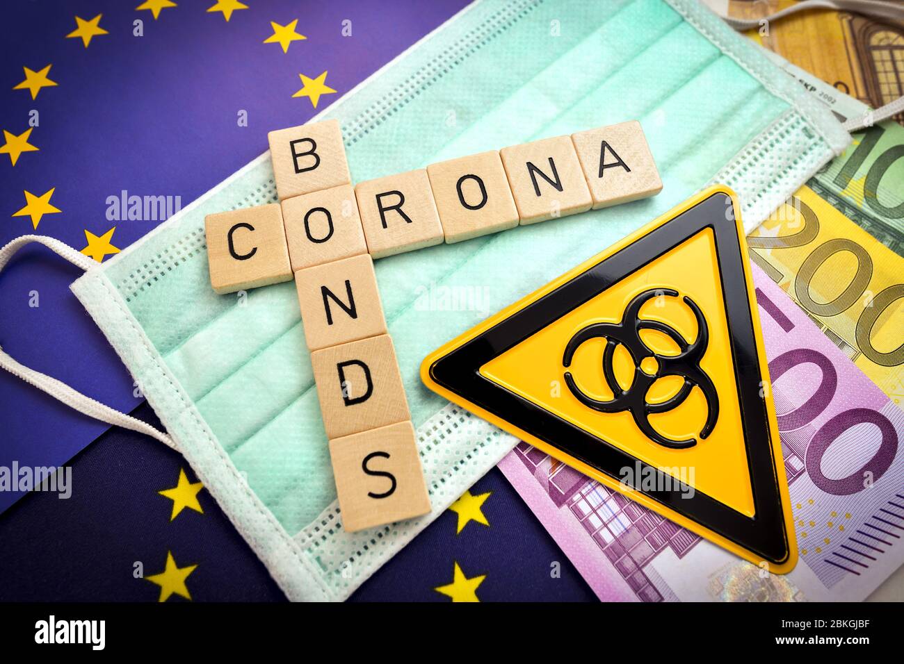 Letras que deletean la palabra corona Bonds en una máscara y bandera europea / Buchstaben bilden den Schriftzug Corona-Bonds auf Mundschutz und Europa-Fahne Foto de stock