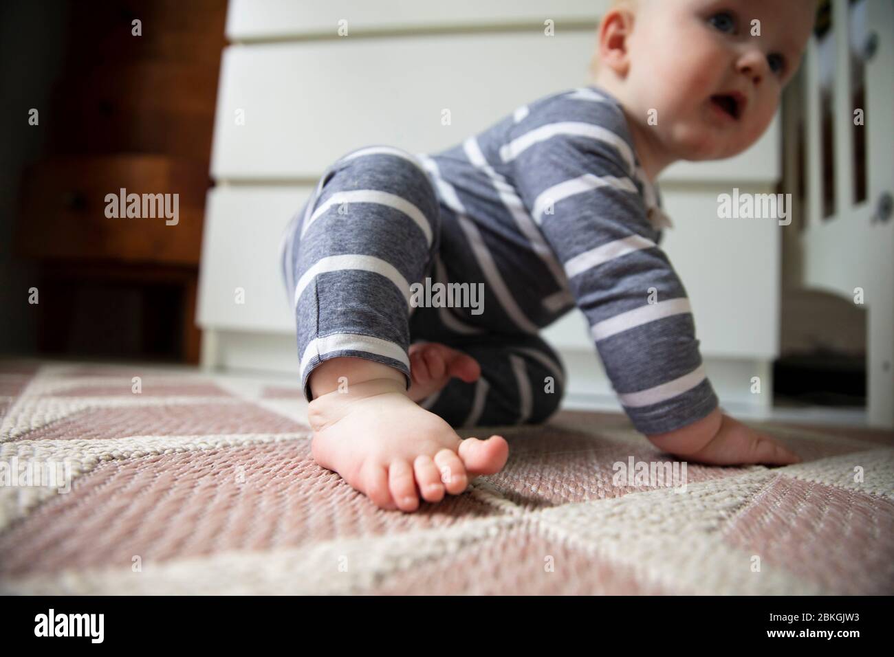 Cerca de un bebé pies y dedos de los pies mientras tratan de gatear en el suelo Foto de stock
