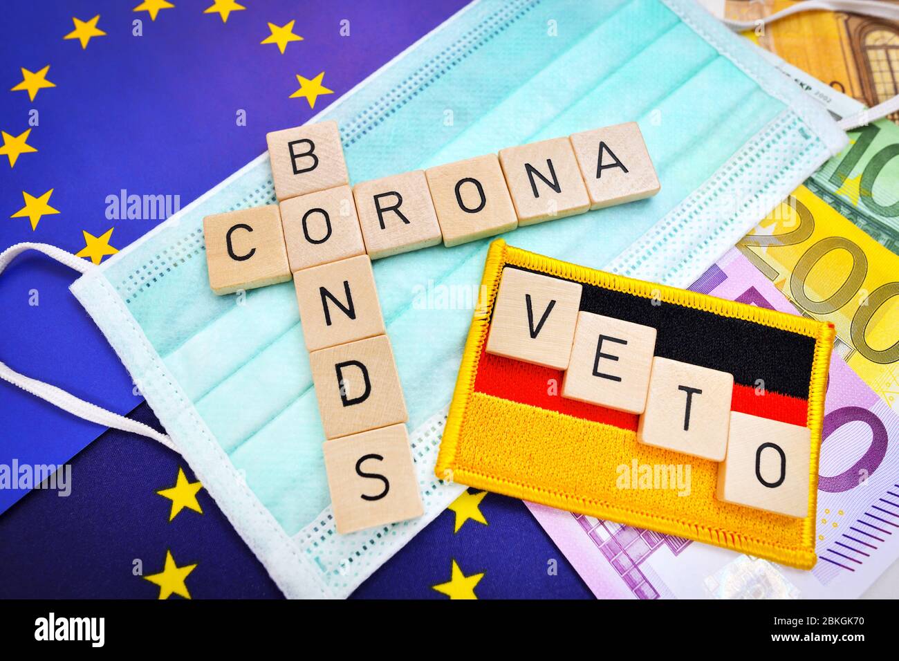 Letras que deletrean la palabra corona Bonds en una máscara y bandera de la UE bandera de Alemania con la palabra veto / Buchstaben bilden Schriftzug Corona-Bonds auf Mun Foto de stock