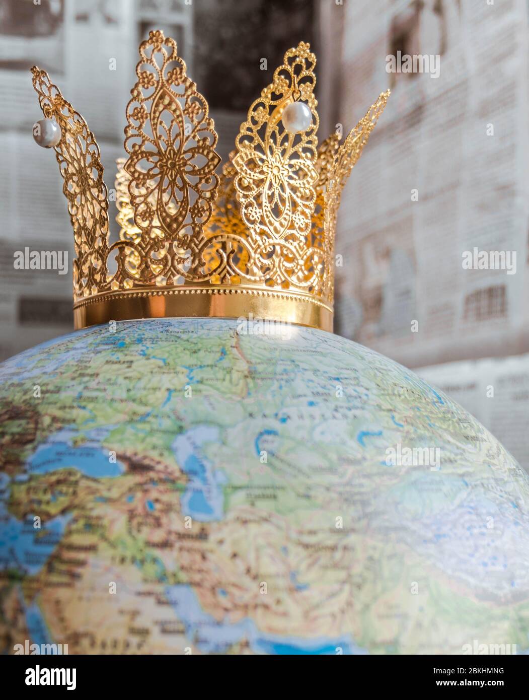 Corona de oro con perlas que representan a Covid-19 en un globo con fondo de periódico bokeh. Foto de stock