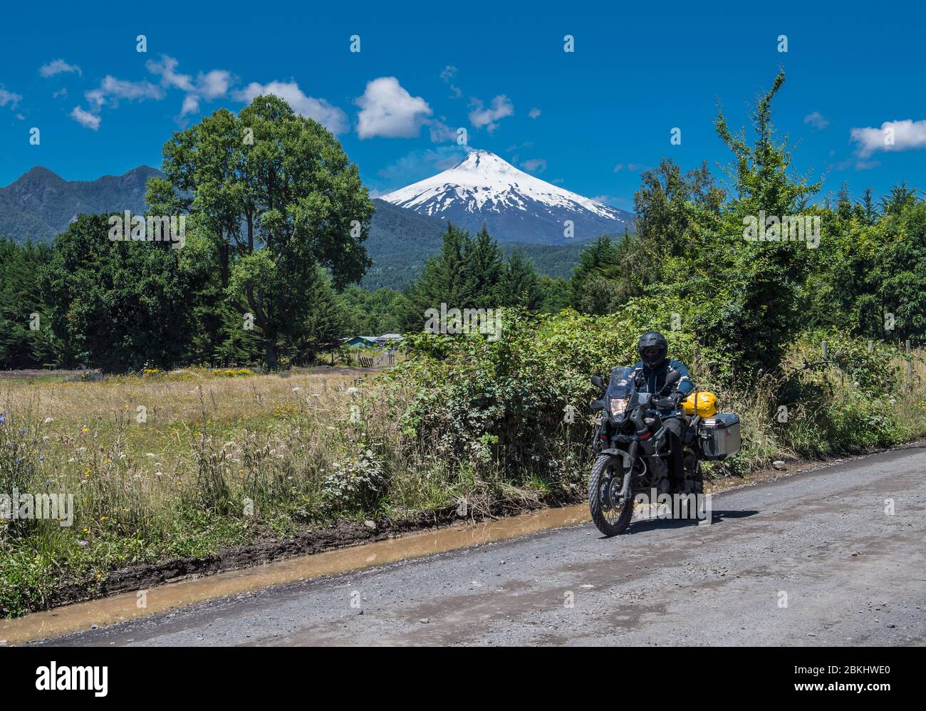 Moto rider pasando el estrato volcán Villarrica, Chile Foto de stock