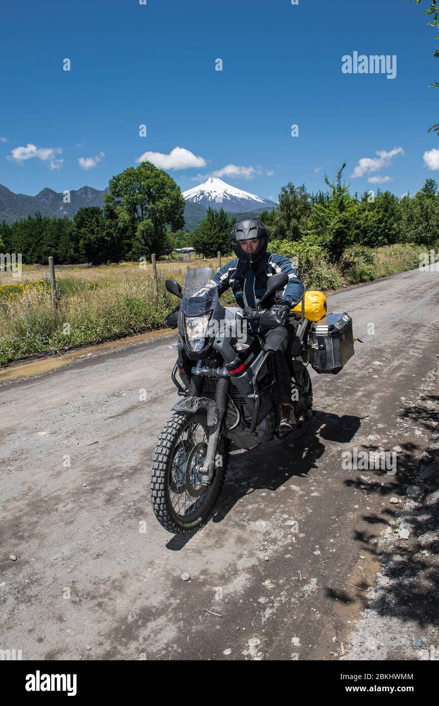 Moto rider pasando el estrato volcán Villarrica, Chile Foto de stock