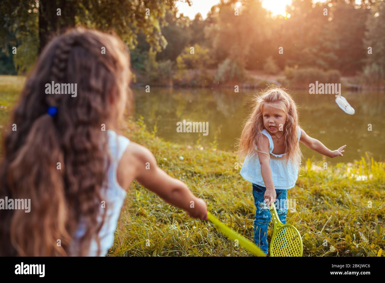 Badminton. Niña jugando badminton con su hermana en el parque de primavera. Los niños se divierten al aire libre. Juegos al aire libre Foto de stock
